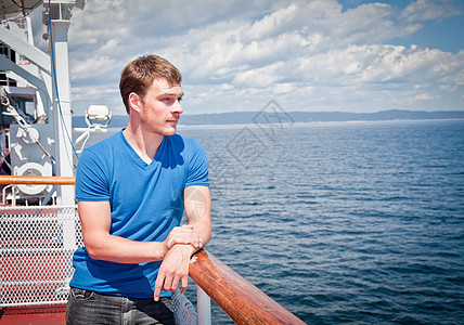 坐在甲板对岸海面的年轻人海洋美丽游艇蓝色幸福男人航行旅游运输闲暇图片