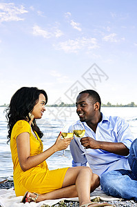 幸福的情侣在海滩上喝酒少数民族女士饮料酒杯天空微笑眼镜男人庆典闲暇图片