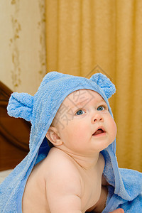 穿着蓝毛巾在床上微笑的婴儿图片