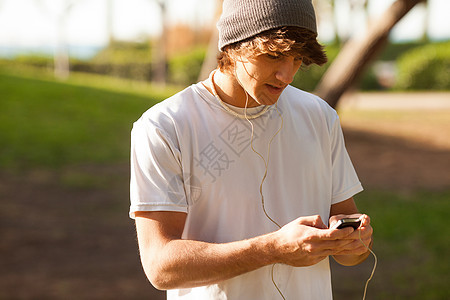 英俊的年轻人在户外咨询电话邮件音乐玩家男人公园背景图片