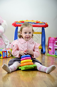 小女孩在一个有玩具的房间里玩彩色金字塔图片