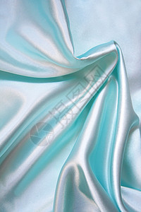 平滑优雅的蓝色丝绸作为背景曲线投标纺织品银色织物材料海浪布料折痕图片