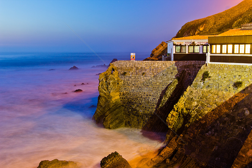 葡萄牙 日落时悬崖上的房子蓝色建筑爬坡阳光照射阳台天空窗户石头烟囱旅游图片