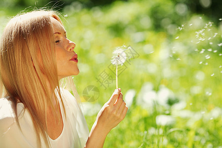 蒲公英女孩女孩吹在花朵上自由头发种子女士生活幸福快乐享受嘴唇植物背景