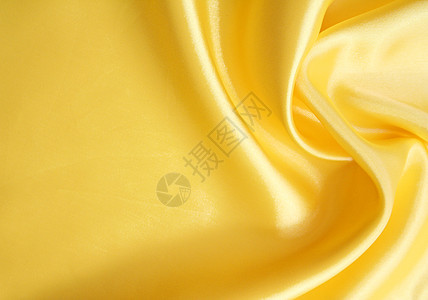平滑优雅的金色丝绸可用作背景黄色投标曲线材料纺织品折痕布料涟漪织物图片
