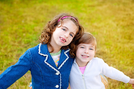 在冬季公园草丛中玩耍的快乐姐妹女孩图片