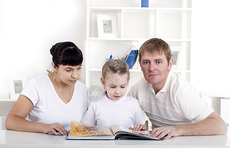 一家人一起阅读一本书女孩展示微笑妈妈夫妻房间男人母亲父亲女士图片