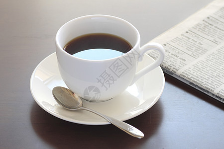 一杯热咖啡和报纸咖啡杯子黑色桌子勺子早餐白色咖啡店休息图片
