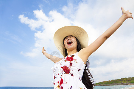 快乐的年轻女子在海滩上举起手来图片