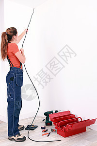 女性电工通过墙壁拉电缆图片