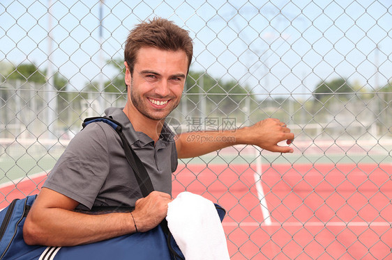粘土网球场旁有运动袋的人图片