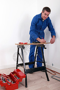 做工作的男人在打工时计算连体衣哈腰铅笔工作台工作服蓝领建设者人士螺丝刀图片