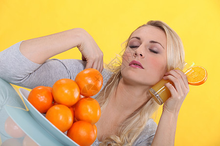 金发金发女人用橙汁杯子刷脸背景图片