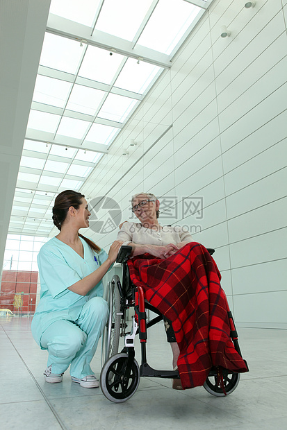 年轻的黑发护士和坐在轮椅上的老妇人在医院图片