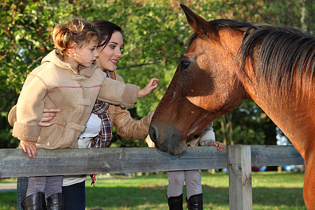 母亲和女儿在马匹旁边图片
