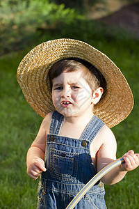 带着草帽的男孩 一个年轻的野外人玩水管图片