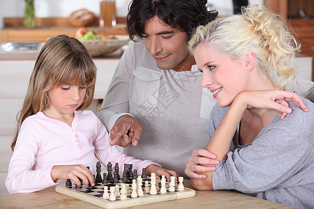 家庭游戏家庭象棋游戏专注学习女孩乐趣头发木板母亲生活父亲女儿背景