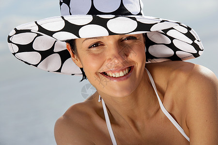在沙滩上戴着时装帽子的迷人女人图片