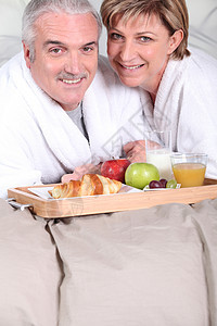 夫妇吃早餐的成熟夫妻包子托盘红色果汁金发女郎长辈浴袍灰色微笑胡子图片