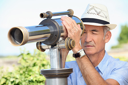 高年男子透过望远镜寻找手镯仪器磁带手表眼睛蓝色镜片花园老人家退休背景图片