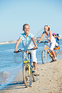 可爱的女孩和她的母亲和兄弟一起骑自行车女士蓝色青少年微笑喜悦金发男生海洋波浪孩子图片