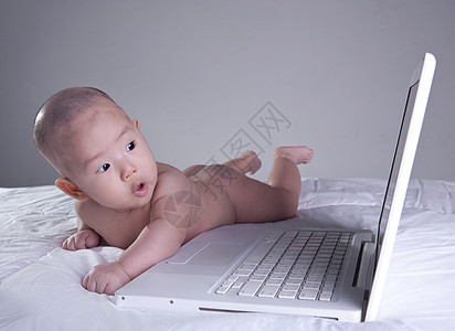 女婴对电脑很感兴趣学习恶作剧电脑显示器好奇心震惊婴儿表情专注头发互联网图片