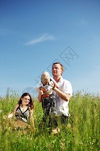 以草为单位的家庭母亲父亲婴儿乐趣太阳花朵男性女士女孩晴天图片