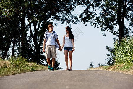 男女青年在夏季户外的一条公路上行走场景友谊娱乐喜悦女士幸福女孩夫妻享受男性图片