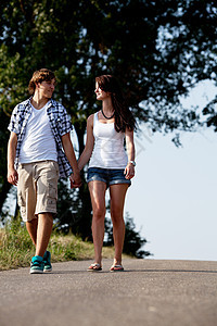 男女青年在夏季户外的一条公路上行走友谊夫妻沥青男性女士公园场景女孩幸福喜悦图片