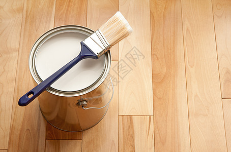 画笔和木地板上一罐白漆图片