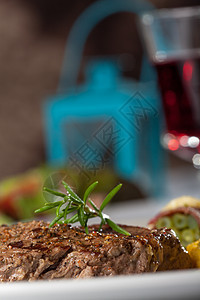 牛排和玫瑰叶蔬菜玻璃盘子餐厅桌子火炬叶子食物迷迭香粮食背景图片