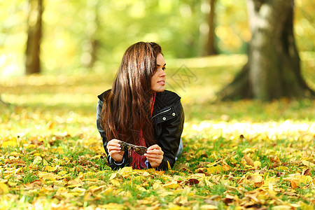 秋叶中的妇女脚尖团体头发女士乐趣橙子女性季节公园金发女郎眼睛图片