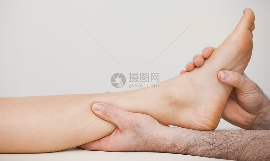 将脚踝按在病人脚踝上的Chiropodist图片