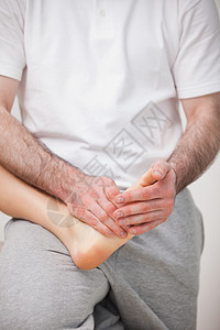 Podiatrist 操纵一个女人的脚 同时握着它图片