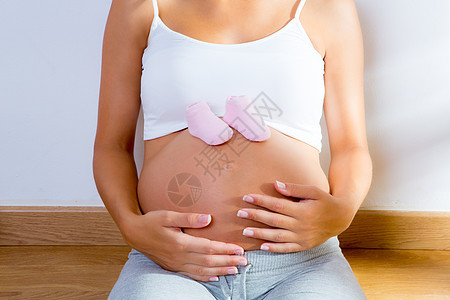 肚子上穿着婴儿鞋的美丽的孕妇女儿母性怀孕家庭女士婴儿女性分娩幸福地面图片