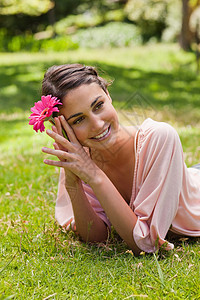 女人躺在她的前面 同时拿着一朵花顶着头部图片