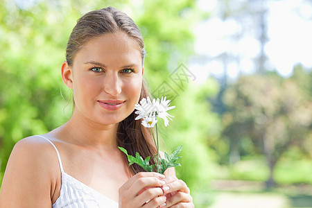 女人在公园里拿着花朵图片