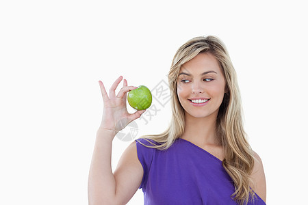 快乐的金发年轻女士 看着绿苹果图片