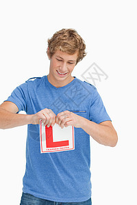 年轻人撕毁一个学习者驾驶标志图片