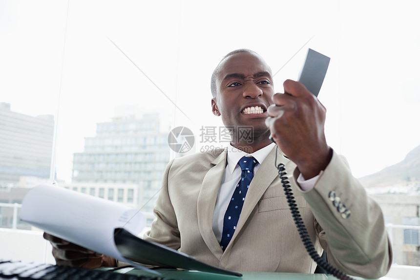 愤怒的商务人士看着他的电话听筒图片