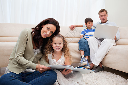 家庭在客厅里闲暇时间微笑沙发乐趣四个人俏皮亲热女性阅读幸福娱乐图片