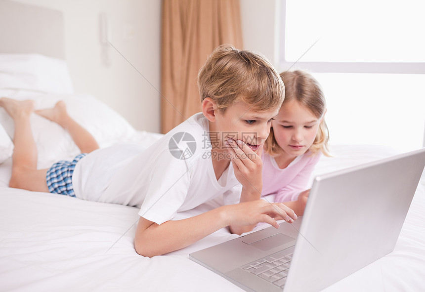 儿童使用笔记本电脑好奇心享受家庭互联网女孩们娱乐男孩们童年幸福闲暇图片