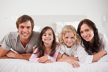 躺在床上的幸福家庭丈夫童年拥抱父亲享受家长女儿卧室团结睡衣图片