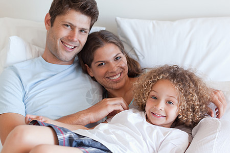 微笑的家庭在床上放松图片