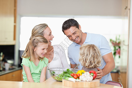 在厨房的幸福家庭沙拉孩子喜悦食物蔬菜午餐四个人家长桌子黄瓜图片