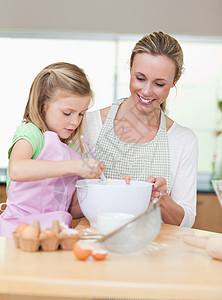 母亲和女儿在为饼干准备钱时微笑厨房童年享受蛋糕烘烤快乐中年人面粉女孩女士图片