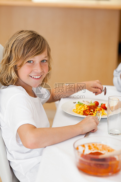 晚餐桌边微笑男孩的侧景图片