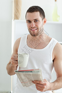 一位微笑的男人在看新闻时喝咖啡的肖像图片