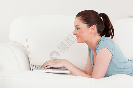 一个美丽的女人的侧面景观 一边用笔记本电脑放松图片