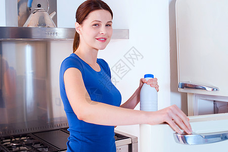 妇女用奶瓶打开冰箱;以及图片